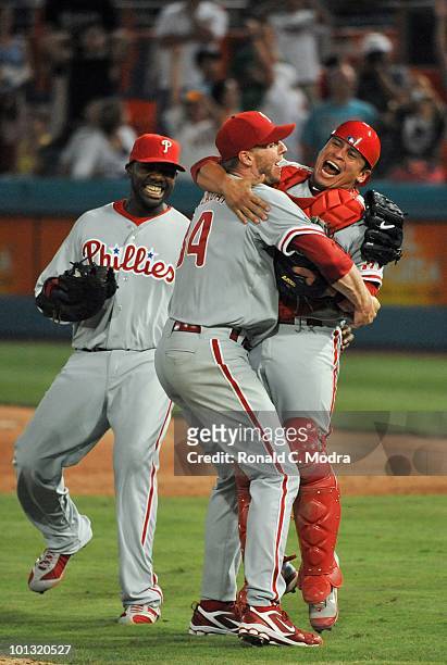 Pitcher Roy Halladay of the Philadelphia Phillies pitches celebrates with teammates Carlos Ruiz and Ryan Howard after pitching a perfect game against...