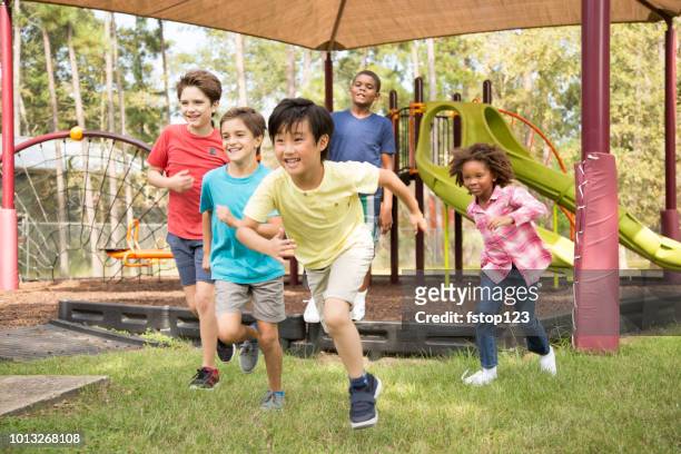 multi-ethnic group of school children running on school playground. - playground stock pictures, royalty-free photos & images