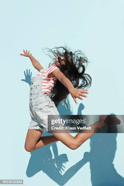 studio shot of girl jumping in sunlight on studio backdrop - style studio day 1 stock-fotos und bilder