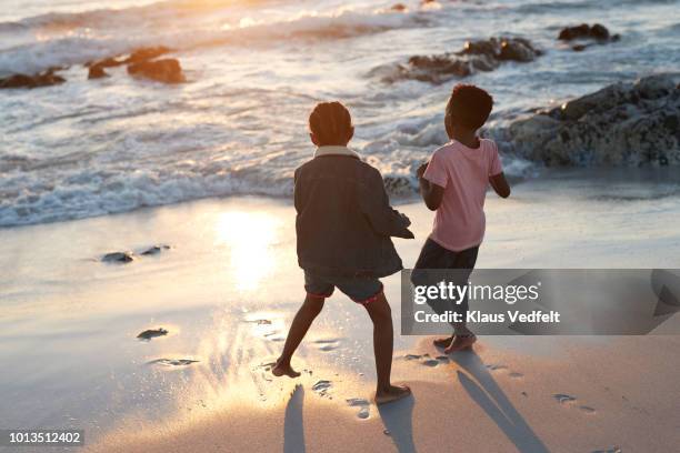 children together playing on beach by the edge of the sea - boy barefoot rear view stockfoto's en -beelden