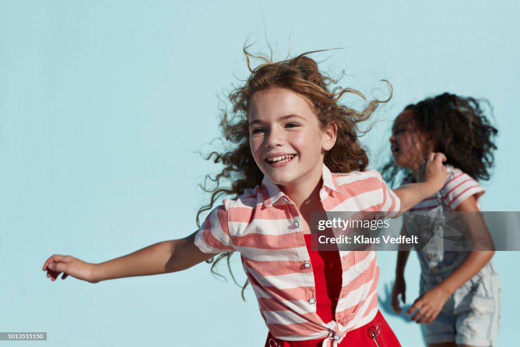 Girl running with arms out, on studio background