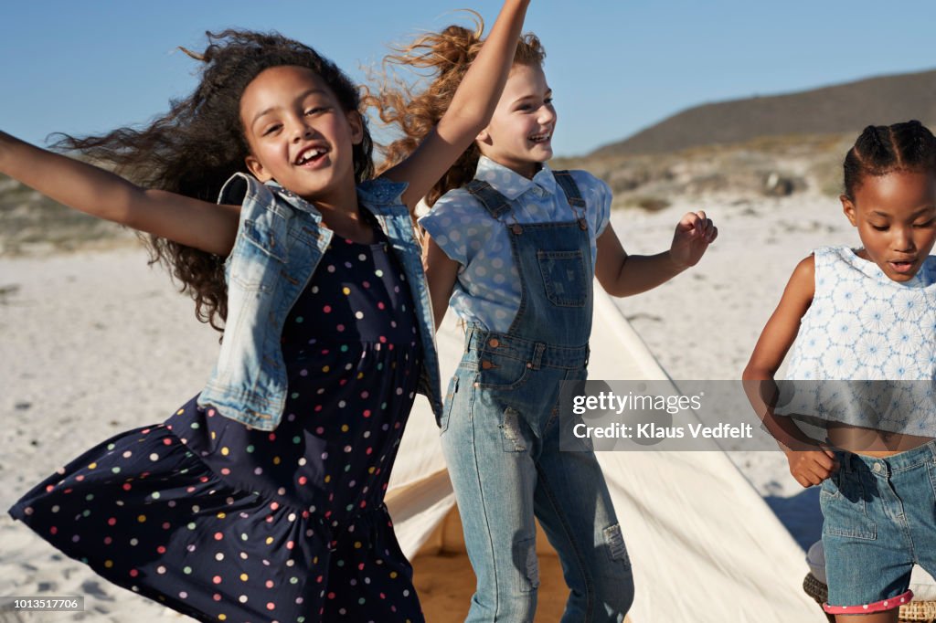 Cute girls laughing & dancing together on the beach