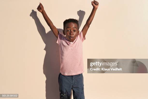 portrait of cute boy with arms in the air on studio backdrop - arms raised stockfoto's en -beelden