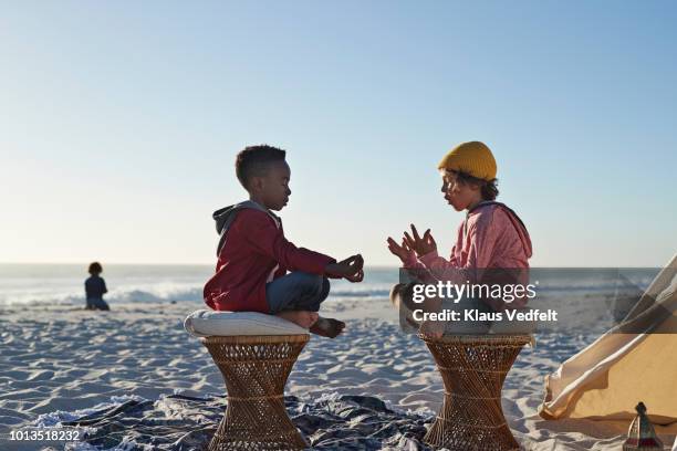 Boys playing together in yoga and meditation positions on beach in summer