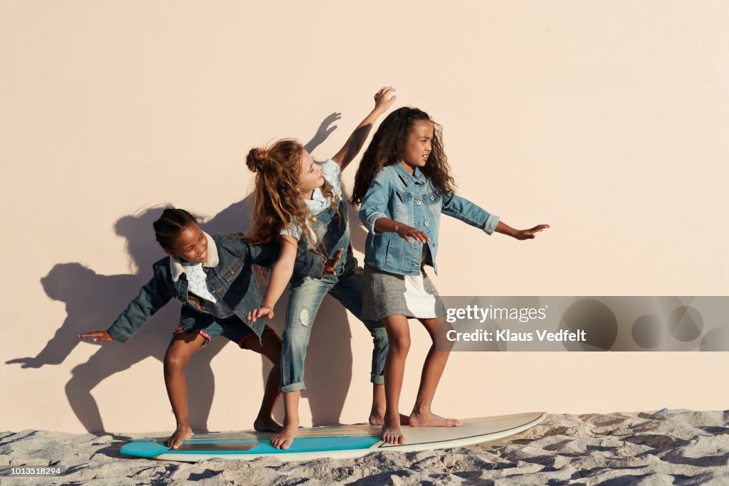 Girls playing on surfboard on the beach, on studio backdrop
