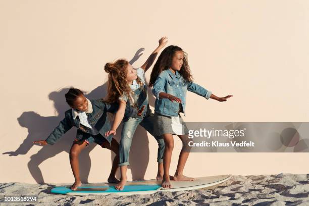 Girls playing on surfboard on the beach, on studio backdrop