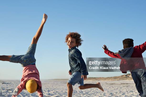 boys together playing on the beach with tent - cartwheel stockfoto's en -beelden