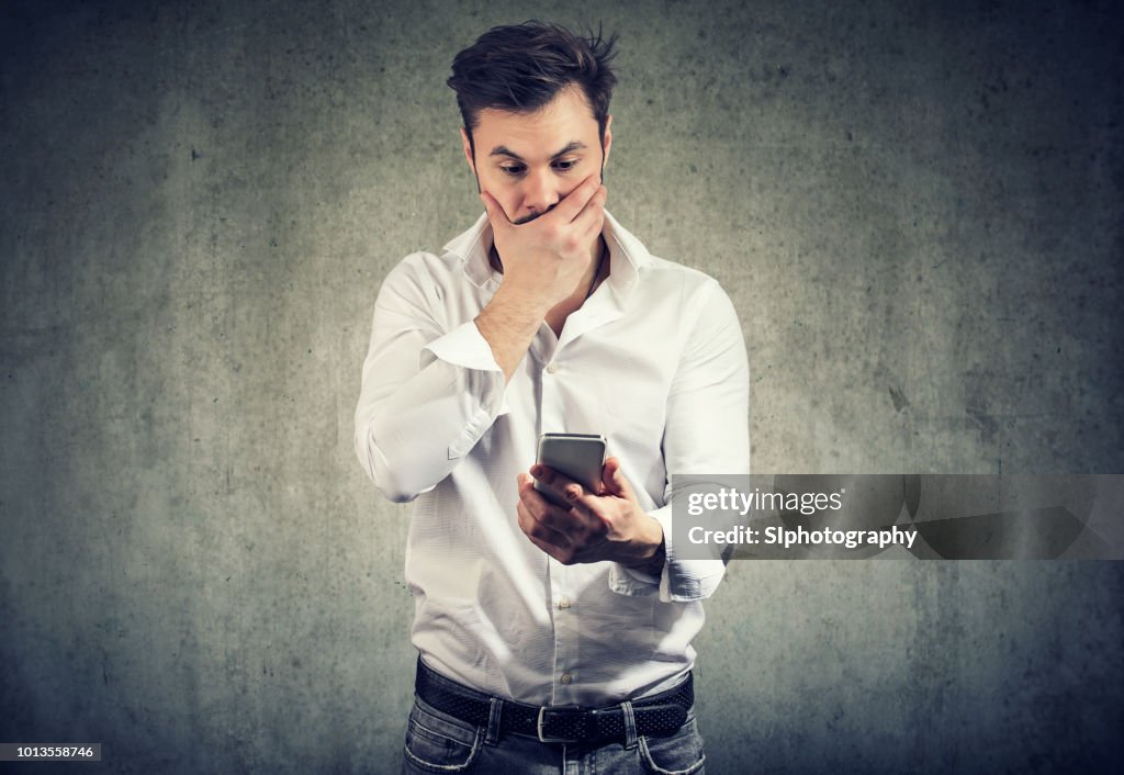 Shocked man watching smartphone having problem