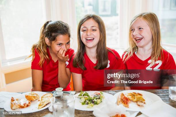 girl whispering to friends at dinner table - eating secret stockfoto's en -beelden