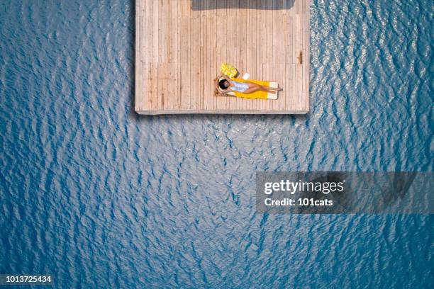 beautiful woman sunbathing alone on a wooden pier in sea aerial photo - beach bag overhead stock pictures, royalty-free photos & images