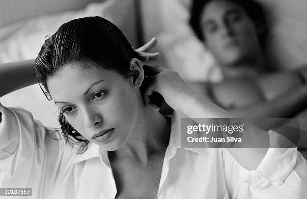 woman combing her hair on the bed with man - black and white lovers stock pictures, royalty-free photos & images