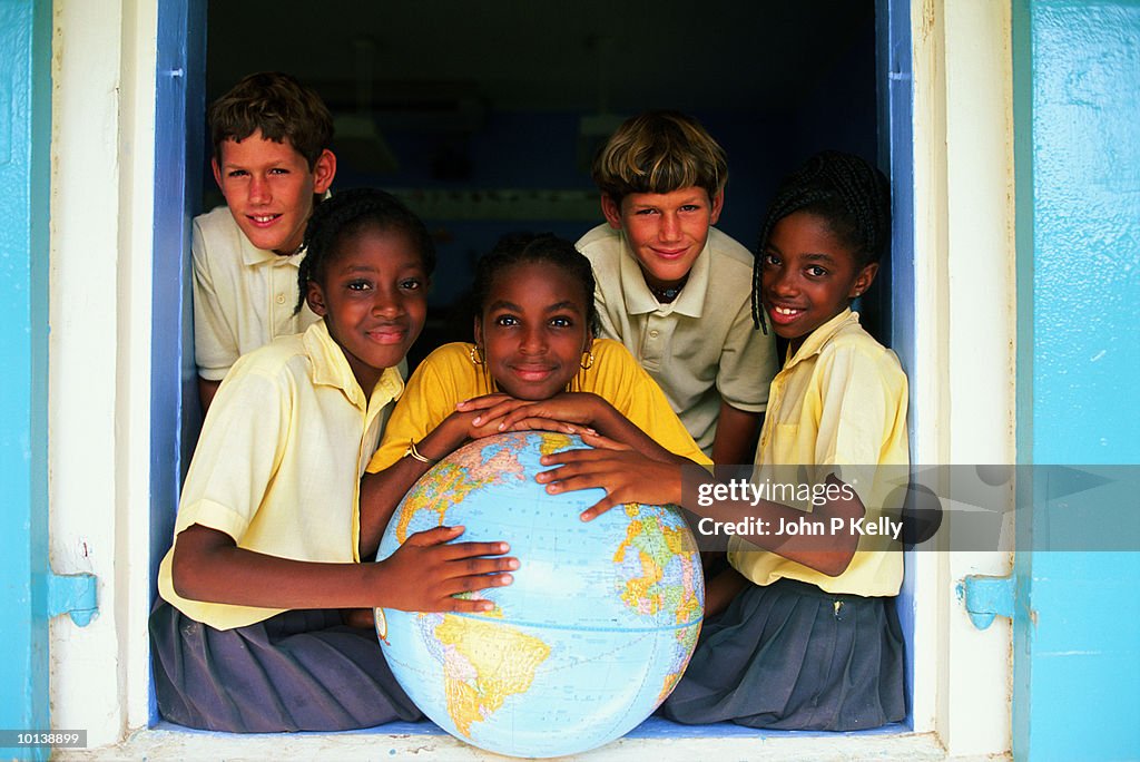 Teenage boys (12-14) posing around large globe