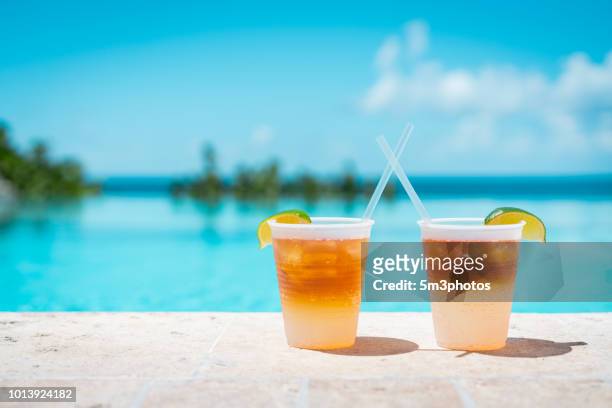 poolside drinks at a tropical resort - sunlight through drink glass stock-fotos und bilder