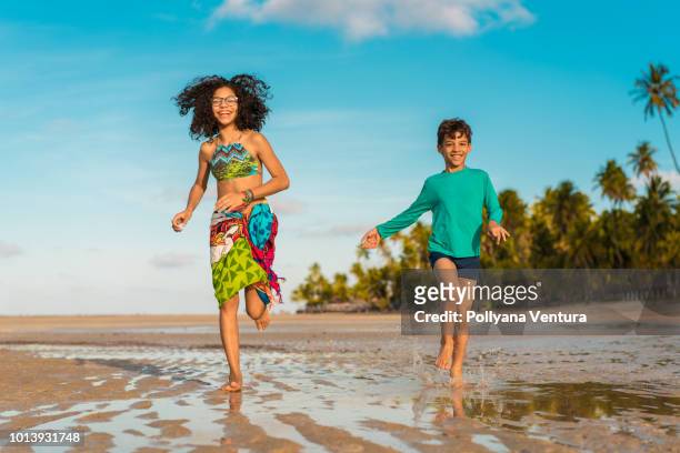 kinder laufen auf carneiros strand in tamandaré, pernambuco, brasilien - hispanic man on beach stock-fotos und bilder