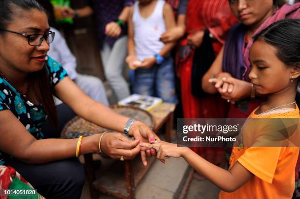 Vendor tries iron ring on little girl to sell during Gathemangal festival in Thimi, Bhaktapur, Nepal on Thursday, August 09, 2018. People wear metal...