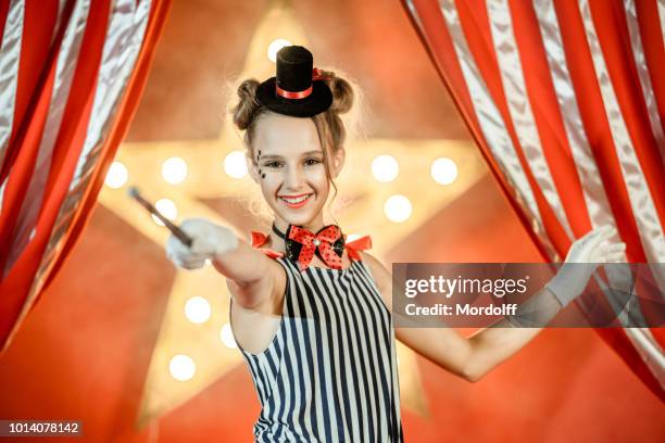 fröhliche junge mädchen illusionist ist winken zauberstab - zirkus kinder stock-fotos und bilder