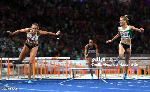 Cindy Roleder of Germany and Elvira Herman of Belarus cross the finish line in the Women's 100m Hurdles Final during day three of the 24th European...