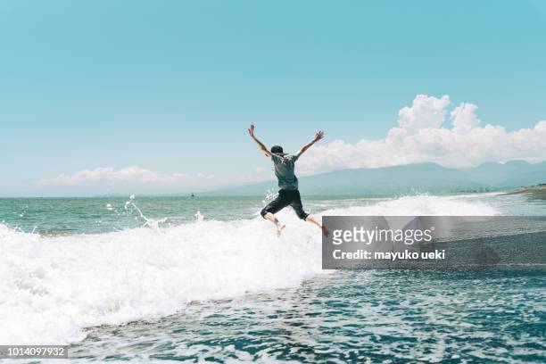 eine frau am strand springen - asian water splash stock-fotos und bilder