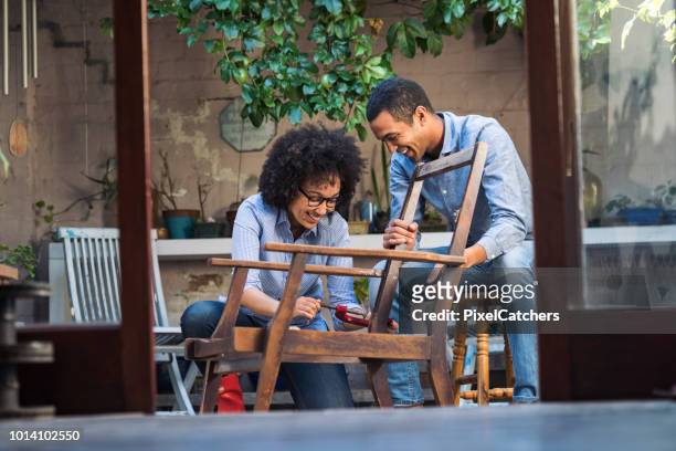 smiling young couple working together to restore a chair - restoring chair stock pictures, royalty-free photos & images