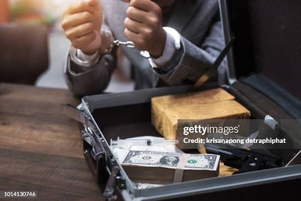 cocaine, marijuana dollars and handgun on wooden table,businessmen caught handcuffed. - marijuana arrest stock pictures, royalty-free photos & images