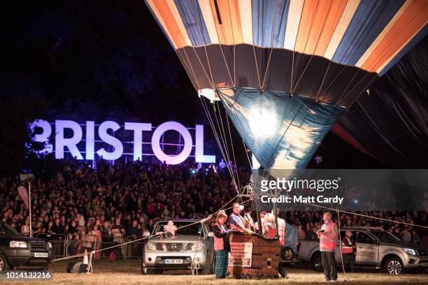 Crowds watch as tethered balloons are illuminated by their burners during the night glow evening event on the first day of the Bristol International...