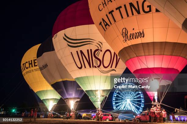 Crowds watch as tethered balloons are illuminated by their burners during the night glow evening event on the first day of the Bristol International...