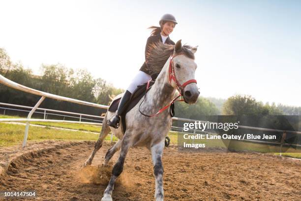 cheerful young woman riding horse - corrida de cavalos evento equestre - fotografias e filmes do acervo