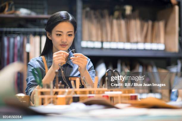 young leather craftswoman working in studio - mani fili foto e immagini stock