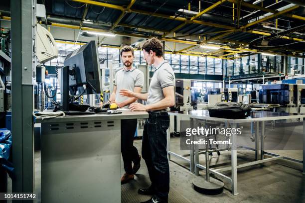 two engineers working at console together - factory stock pictures, royalty-free photos & images