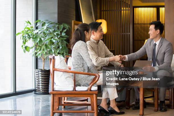 confident financial consultant shaking hands with mature couple - asian couple having hi tea stockfoto's en -beelden