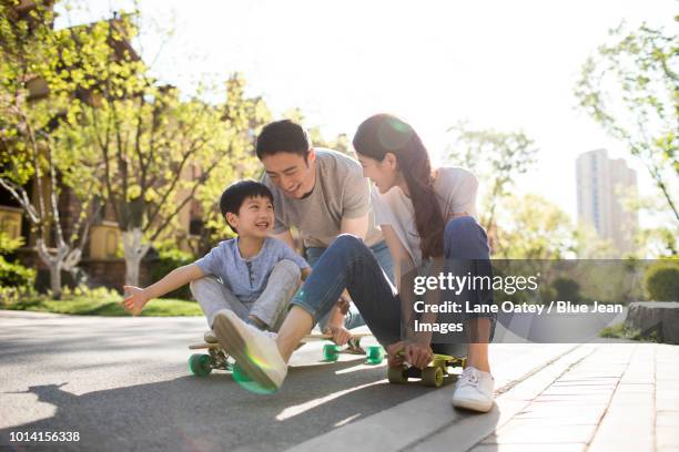 happy young family playing with skateboards - china balance stock pictures, royalty-free photos & images