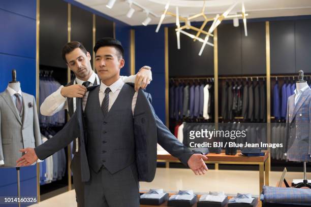 fashion designer examining suit on customer - clothes customization stockfoto's en -beelden