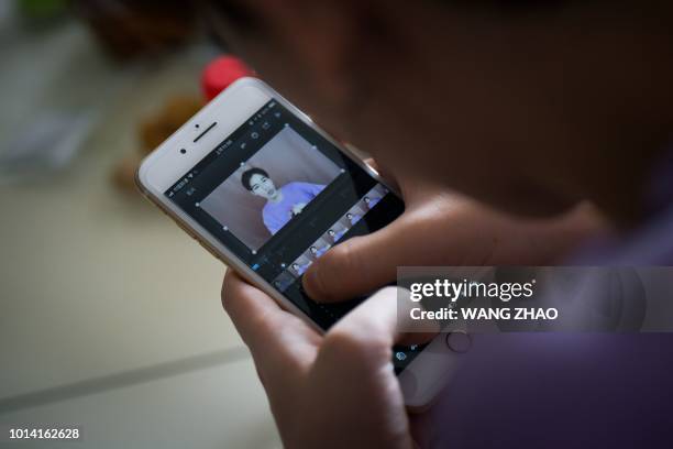 This picture taken on July 29, 2018 shows Jiang Cheng using his mobile phone to edit video at his home in Beijing. - When Jiang Cheng first tried a...