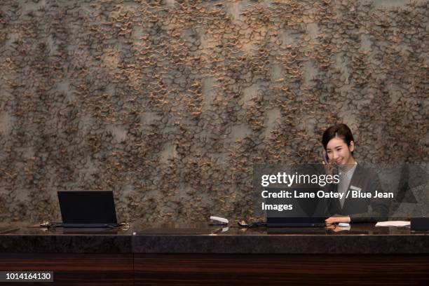 cheerful hotel receptionist talking on the phone - vip reception stock pictures, royalty-free photos & images