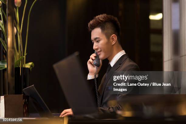 cheerful hotel receptionist talking on the phone - reception 2017 ストックフォトと画像