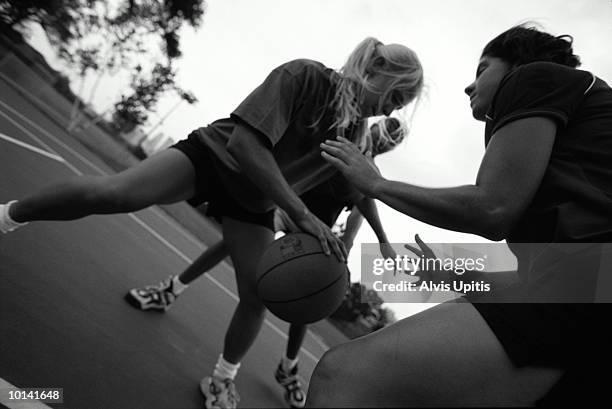 young women playing basketball, low angle view (b&w) - black and white basketball court stock pictures, royalty-free photos & images