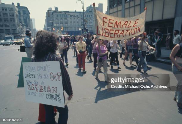 Female Liberation' banner at an LGBT parade through New York City on Christopher Street Gay Liberation Day 1971. One person carries a placard reading...
