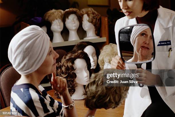 hospital staff helps cancer patient with selecting wig - perücke stock-fotos und bilder