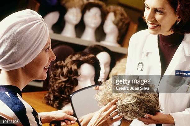 hospital staff helps cancer patient with wig selection - perücke stock-fotos und bilder