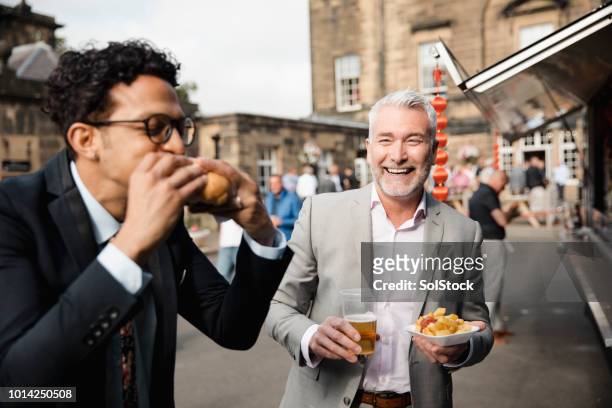 men enjoying burger, chips and beer outside - upper class stock pictures, royalty-free photos & images