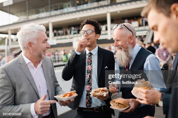 männer, die spaß über einen burger und pommes frites - newcastle races stock-fotos und bilder