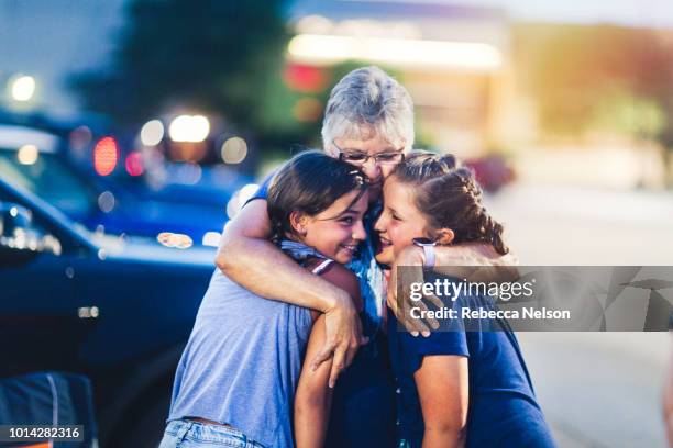 grandmother hugging two of her granddaughters at night during independence day celebration - womens issues stock pictures, royalty-free photos & images