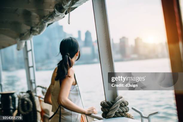 young woman looking over the spectacular city skyline of hong kong at dusk while riding on star ferry - 渡輪 個照片及圖片檔