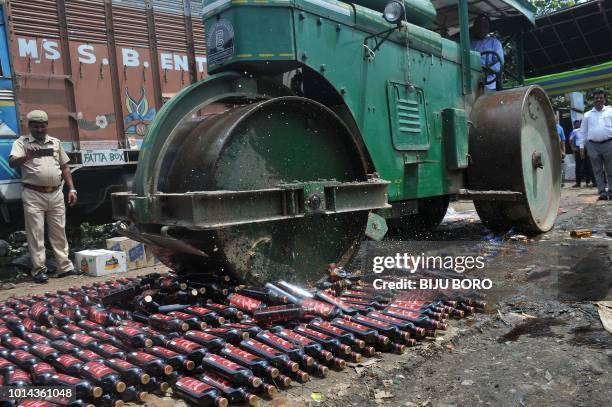 Road rollercrushes crushes liquor bottles which were seized by the sleuths of the department for illegal trading in Guwahati on August 10, 2018. -...