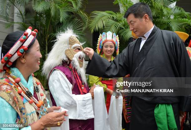 Lobsang Sangay, president of Central Tibetan Administration looks at a traditional mask worn by a Tibetan man as he waits to greet the spiritual...