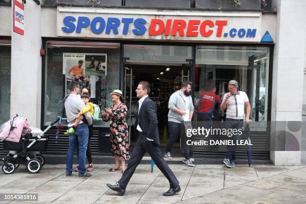 Pedestrians walk past the entrance of a Sports Direct store in central London on August 10, 2018. - House of Fraser, the Chinese-owned UK department...