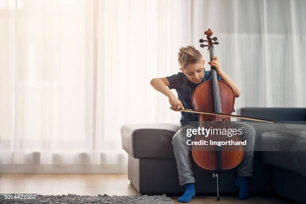 little boy practicing cello at home - child musical instrument stock pictures, royalty-free photos & images