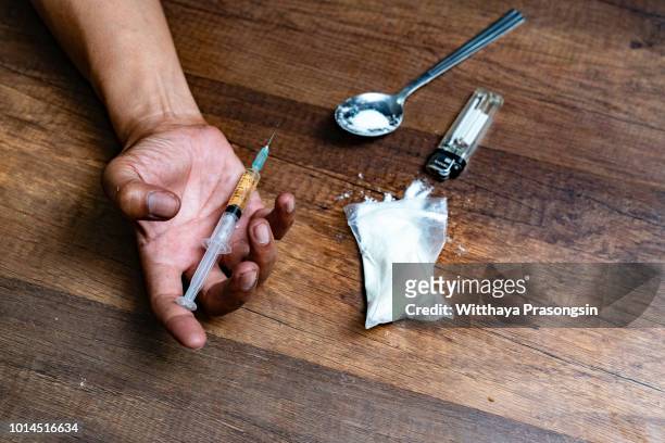 human hand of a drug addict and a syringe with narcotic syringe lying on the floor. anti drug concept. - drug addiction stock pictures, royalty-free photos & images