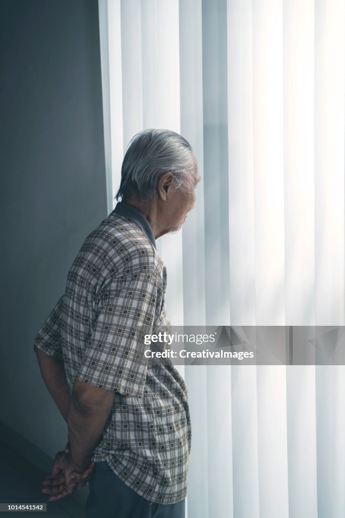 Einsamer senior Mann am Fenster stehend