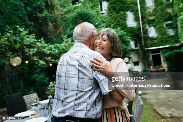 elderly couple embracing before bbq with family - senior embracing stock pictures, royalty-free photos & images
